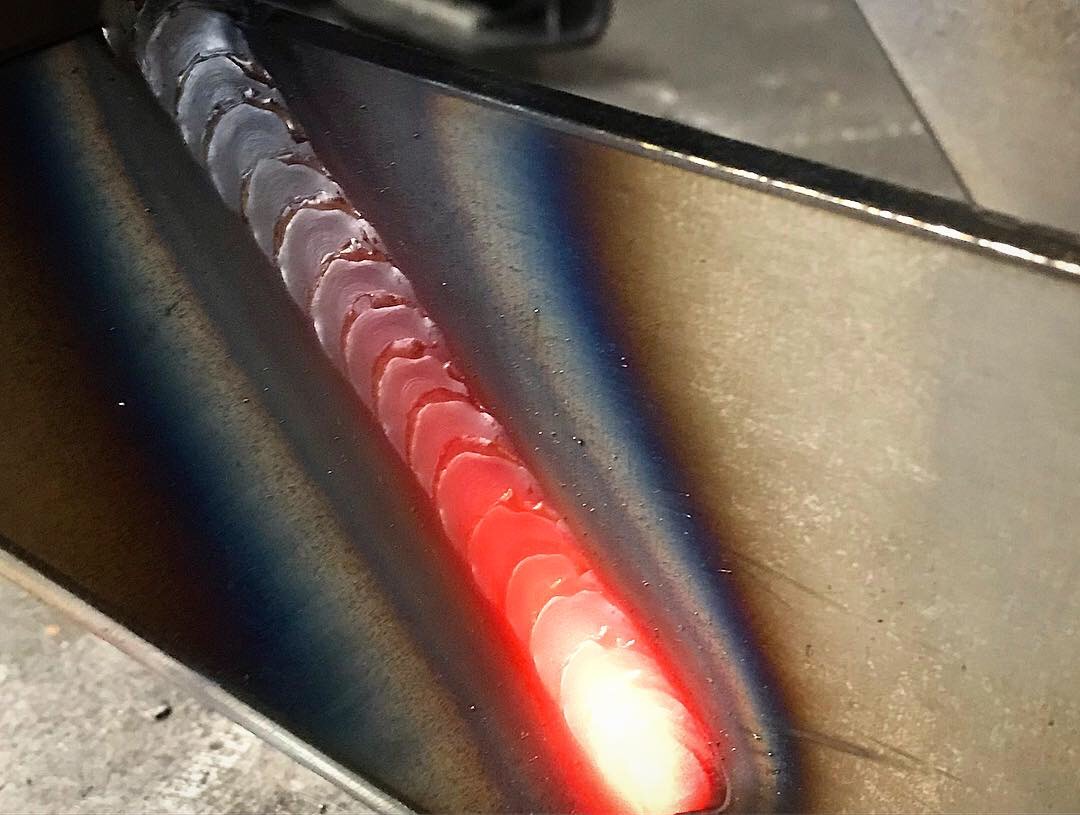 Detailed view of a glowing, freshly welded bead on a metal joint, showcasing the precision and quality of the welding process.